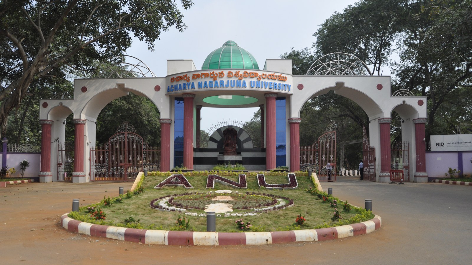 Intrarea principală a Acharya Nagarjuna University, cu inscripția numelui instituției și răzoarele ANU, Guntur, Andhra P…