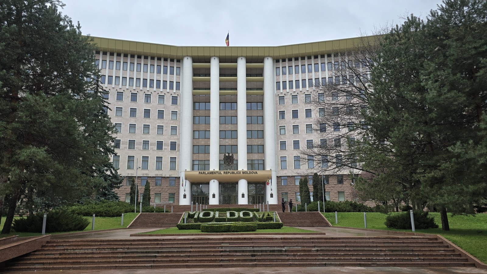 Fațada Parlamentului Republicii Moldova din Chișinău, cu coloane albe, steagul de pe acoperiș, inscripția PARLAMENTUL RE…