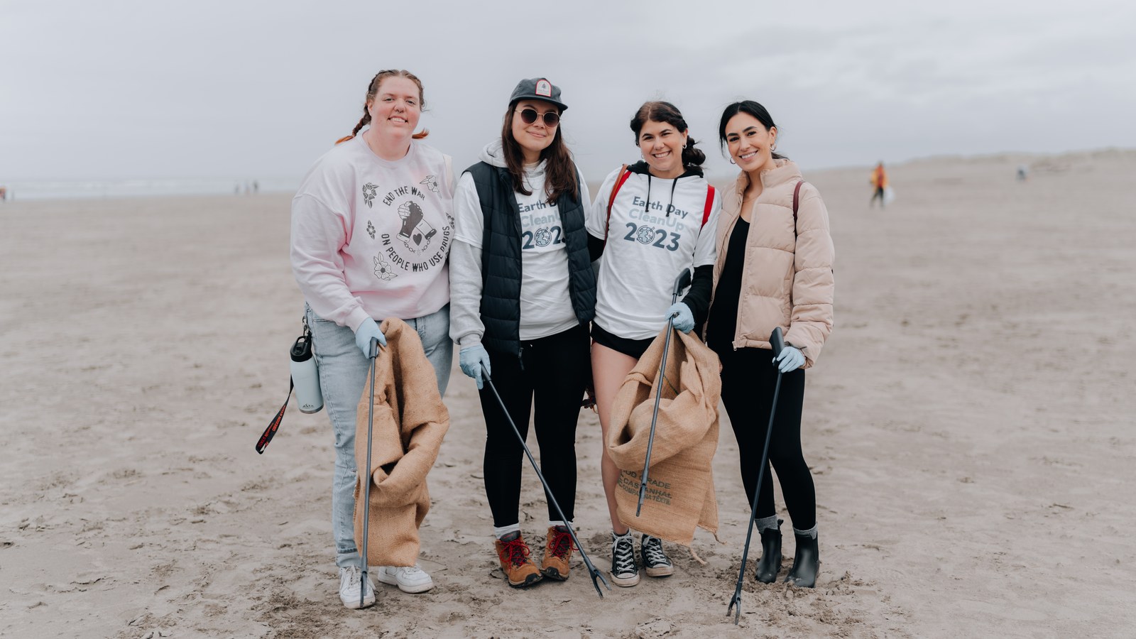 Volunteers with bags and gloves at a beach cleanup, archive photograph from 2023