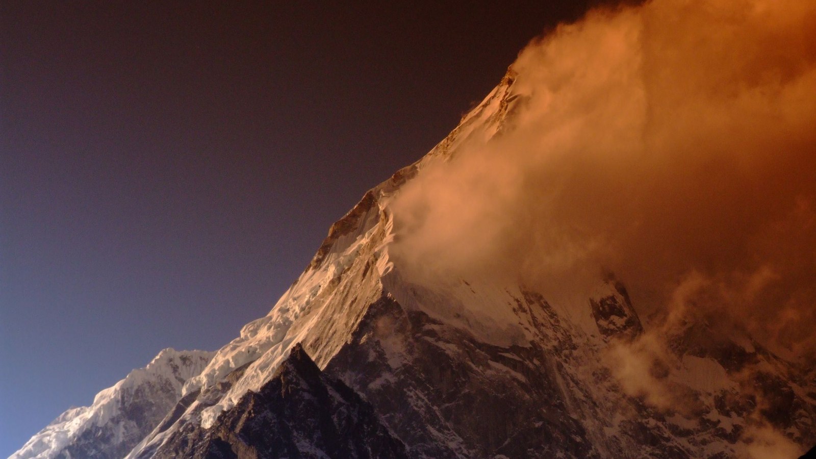 Vârf înzăpezit în masivul Langtang, Himalaya, cu nori la apus