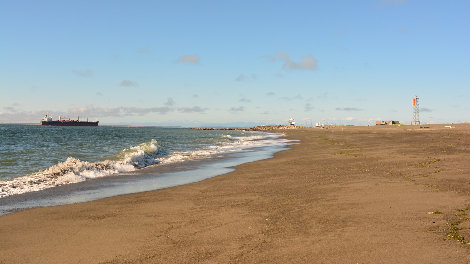 Val care se sparge pe țărm la Westport, Washington, cu plajă și larg vizibile