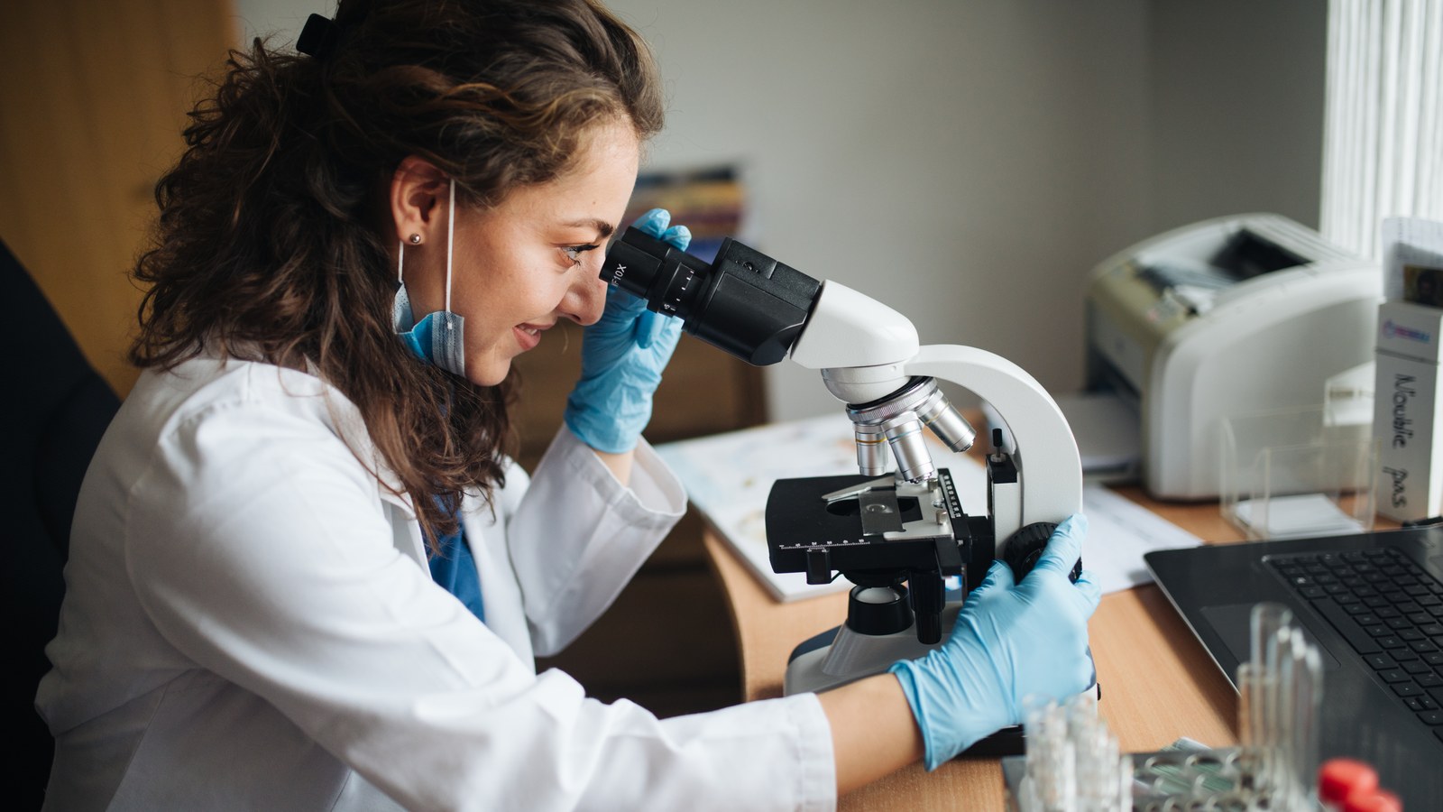 A researcher at a microscope in a laboratory, an illustrative image