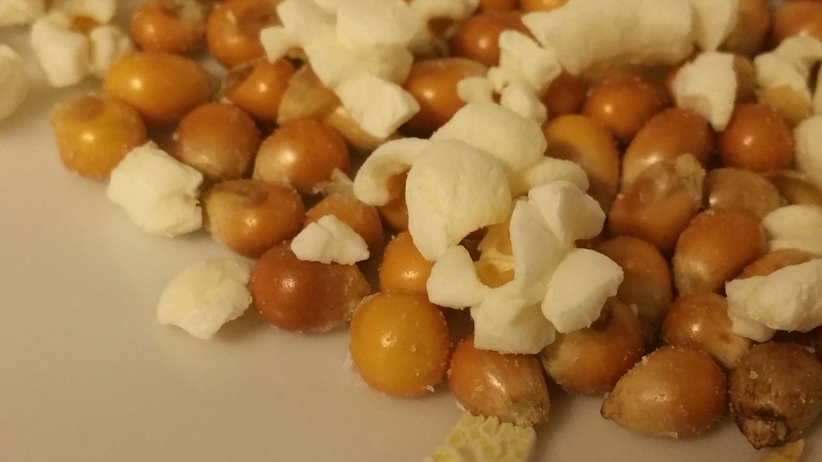 Boabe de popcorn și floricele pe o farfurie; nu o înregistrare a pocnirii la 180 °C