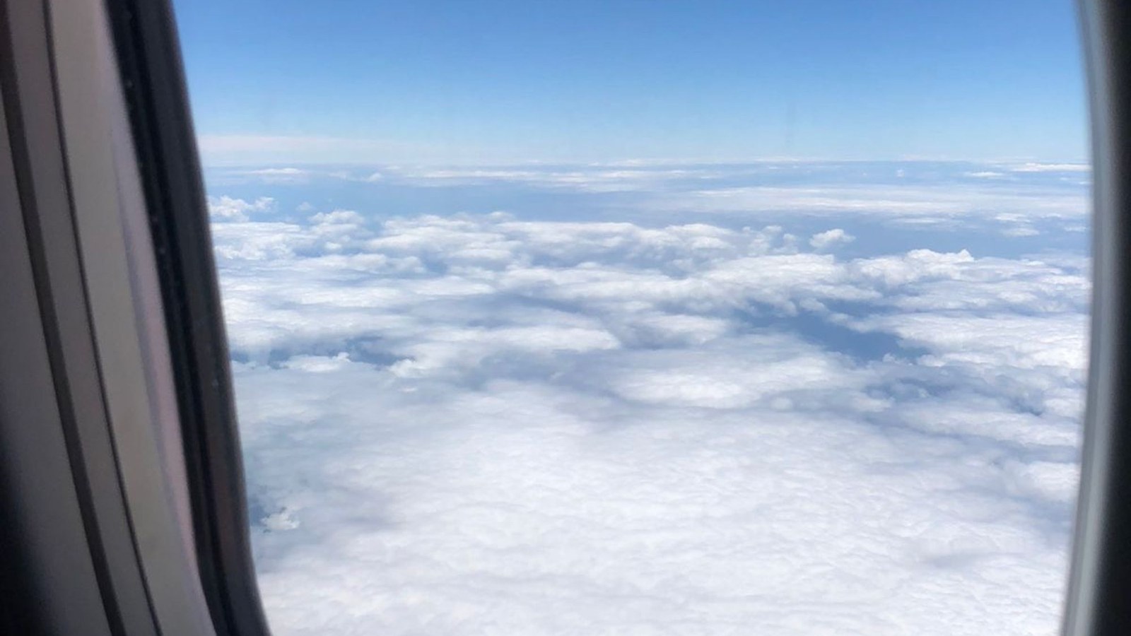 An aircraft window seen from the cabin, with sky outside