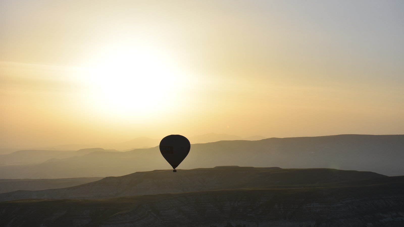 Hot-air balloon at sunrise over a rural Cappadocia landscape